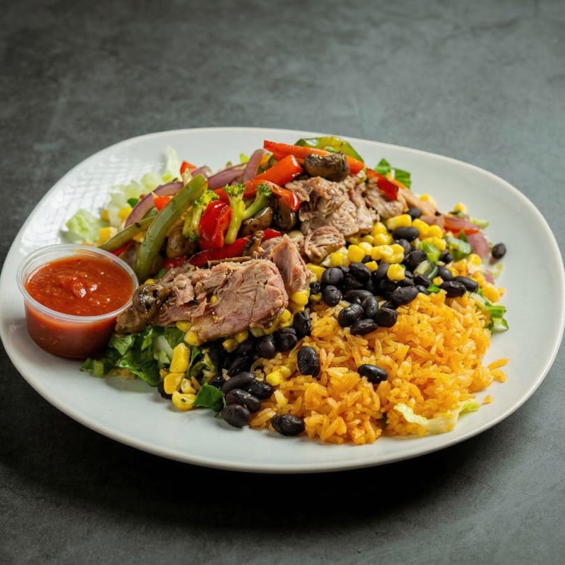 Mucho Loco Mexican Restaurant's colorful bowl with rice, black beans, meat, and mixed vegetables, with a side of salsa.